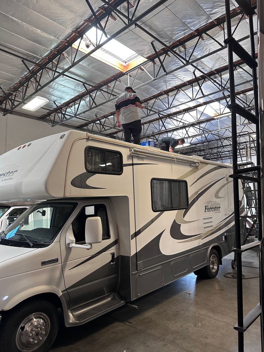 Technicians working on the roof of a Forest River motorhome in the shop